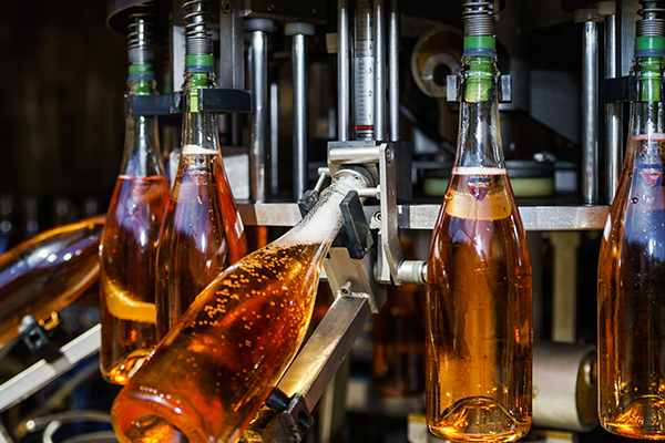 Bottling process of sparkling wine with automated machinery in a factory setting.