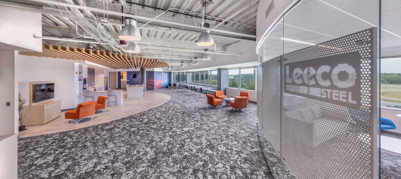 Modern office lobby with orange chairs, abstract ceiling design, and Leeco Steel signage.