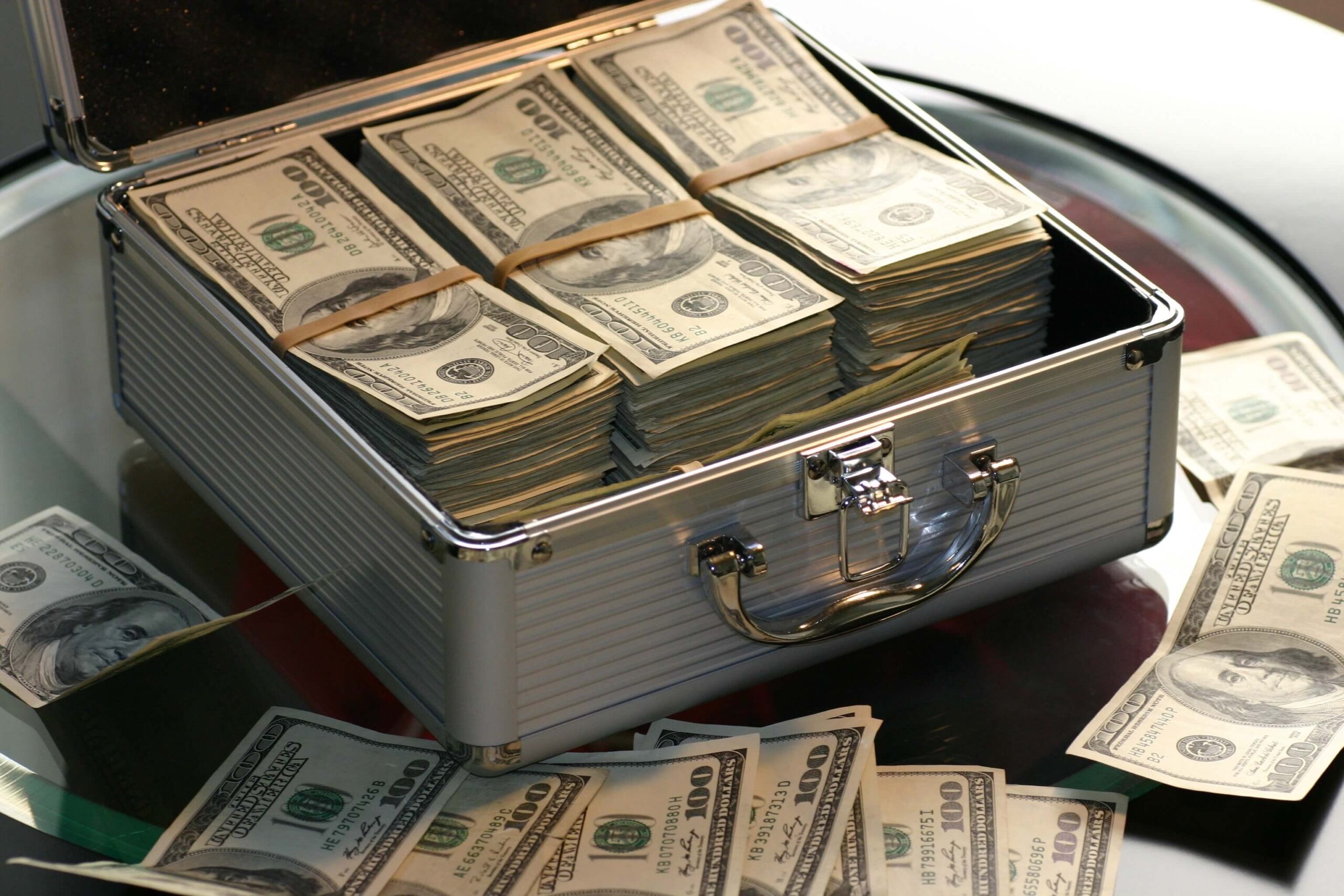 Open briefcase filled with stacks of hundred-dollar bills, symbolizing wealth and financial success.