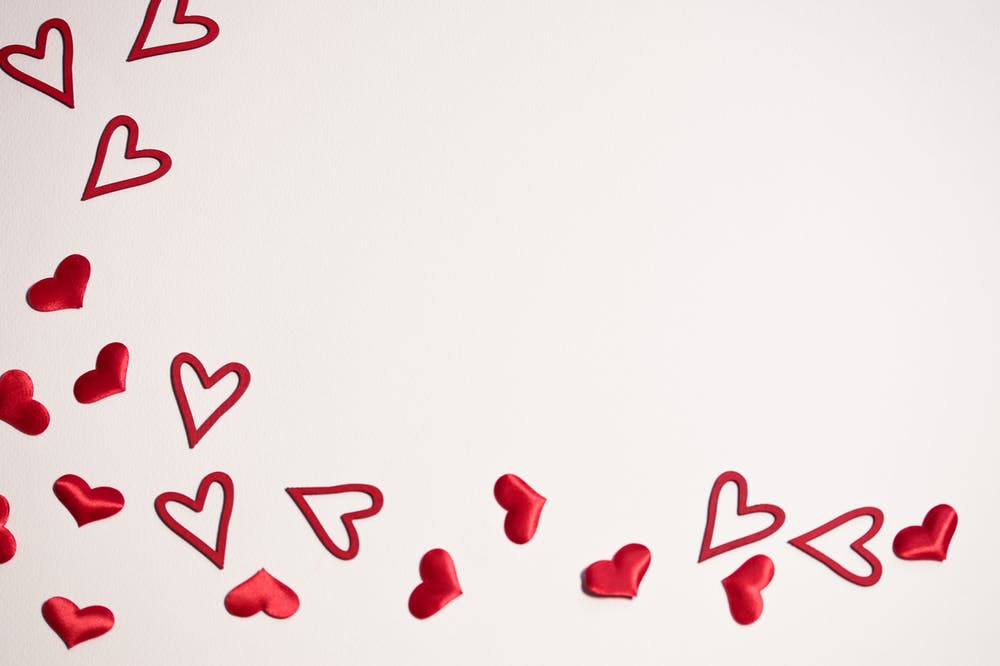 Red heart shapes scattered on a white background, perfect for Valentine's Day or romantic themes.