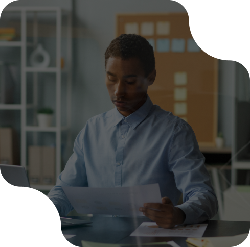 Man in office reviewing documents at desk, focused and professional setting.