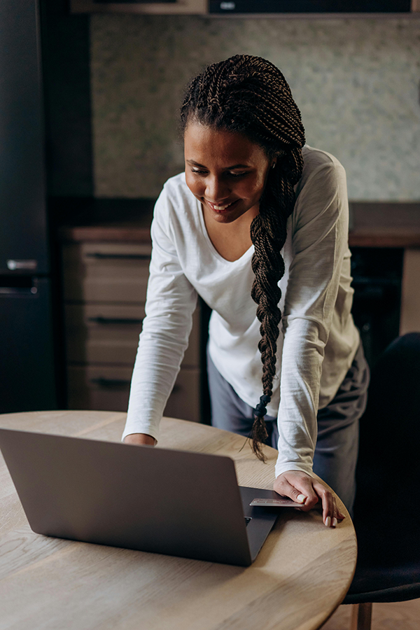 Person using a laptop at home, smiling and engaged, during a work or study session in the kitchen.